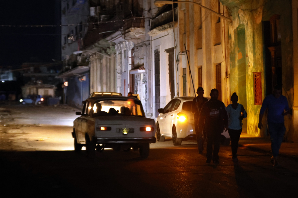 Personas caminan por un sector sin servicio eléctrico a causa del tercer apagón nacional el jueves 5 de diciembre, en La Habana. Foto: EFE