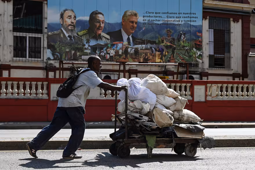 a-cuban-man-pushes-a-wheelbarrow-of-waste-on-a-2ZP4HULUANCMVFRJ5NI5HVWQMA