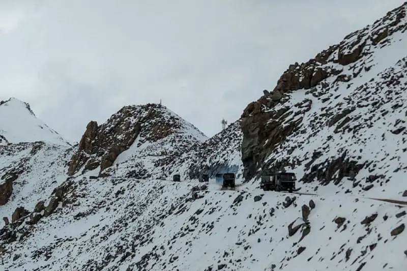 Indian army vehicles drive on a road near a mountain pass in the Ladakh region of India | AFP via Getty Images